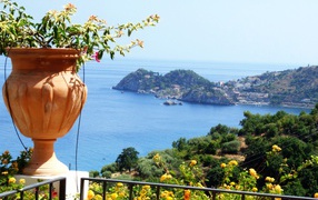 Кувшин с цветами на фоне залива на острове Сицилия, Италия