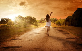 Ballerina on the road against the sunset