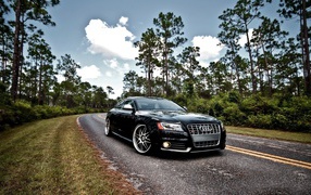 Luxury black Audi S5 on the highway in the woods