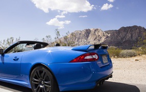 Blue convertible Jaguar mountains in the background