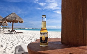 Бутылка холодного пива на столе на пляже