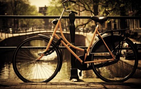 Оранжевый велосипед прислонен к перилам