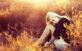 Блондинка сидит среди кустарников