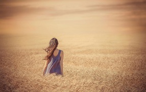 Girl among a field of ripe wheat