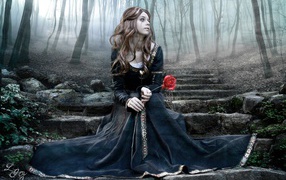 Girl in a black dress and a rose in her hand sitting on stone stairs