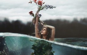 Девушка стоит в воде с букетом в руке