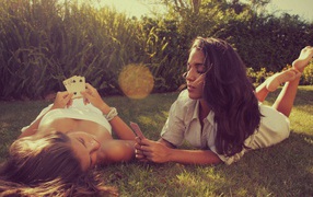 Девушки играют в карты на газоне