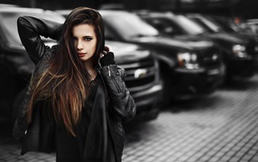 Черноволосая девушка на фоне черных автомобилей