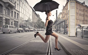 Девушка бежит с зонтом через улицу