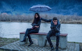 The guy holding an umbrella over the girl in the rain