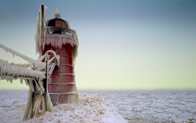 Red lighthouse covered in ice and icicles