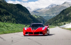 Красный спортивный автомобиль Ferrari FXX на фоне гор