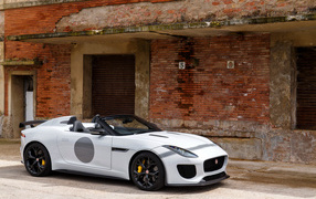White Jaguar F-Type car near the red brick wall