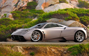 Silvery fast car Pagani Huayra on the highway at the cliff