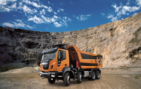 Orange truck Astra HD9 84.50 8 × 4 in the quarry under the blue sky