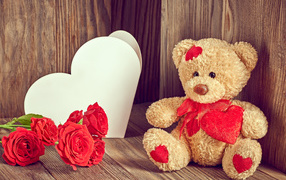 Плюшевый медведь с большим белым бумажным сердцем и красными розами