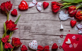 Красные тюльпаны с сердечками и бантиками на деревянной поверхности