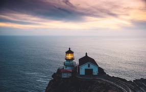 Lighthouse on the cliff against the background of the ocean horizon