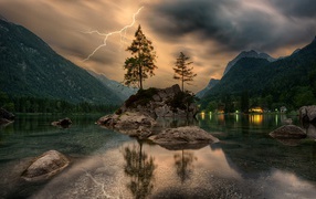 Lightning in thunderclouds above the mountain lake