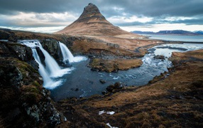 Гора и водопад у реки в Исландии  
