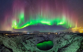 Northern lights above the snow-covered crater of the volcano