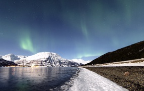 Northern lights in the sky above the snow-capped mountains
