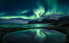Northern lights in the starry sky above the mountain lake