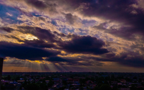 The rays of the sun make their way through the clouds over the city