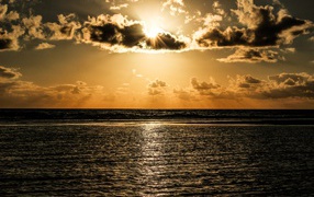 Солнечные лучи пробиваются сквозь облака над океаном