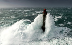 The surging wave envelops the lighthouse