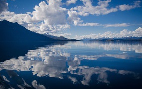 White clouds in the blue sky are reflected in the water