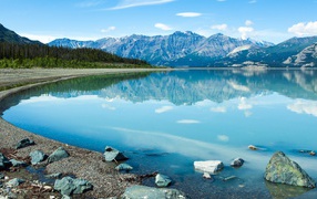 The mountains are reflected in the blue water of Lake Clouayne, the National Park in the Yukon area, Canada.