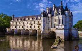 Ancient Chenonceau castle on the water under the blue sky, France