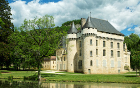 Ancient castle by the pond in the green garden, France