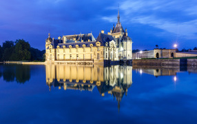 The ancient Chantilly Castle is reflected in the pond, France
