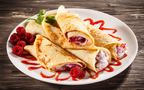 Delicious pancake rolls with sour cream and raspberries for the holiday Maslenitsa