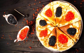 Pancakes with black and red caviar on a wooden table on Pancake week