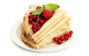 Thin pancakes with raspberries and red currants on a white background on Shrovetide