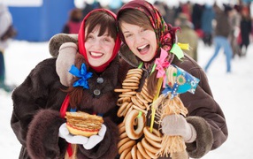 Two girls with pancakes and donuts at Shrovetide