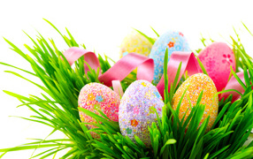 Easter eggs in green grass with a pink ribbon on a white background