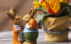 Figurines of Easter bunnies on a table with tulips