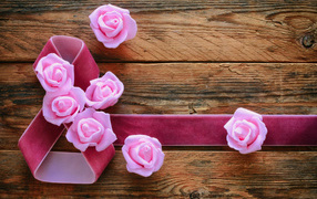 Eight of a ribbon with pink roses on a wooden background on International Women's Day