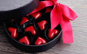 A box of chocolates in the shape of heart with a red ribbon