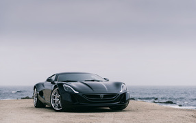 Black sports car Rimac Concept One on the background of the ocean