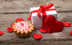 Gift with red hearts and a cake on the table