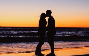Kiss of a loving couple on the beach at sunset