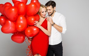 Loving couple with red balloons in the shape of heart