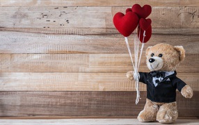 Teddy bear with hearts on a wooden background