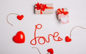 Надпись любовь красными нитями на сером фоне с сердечками и подарками