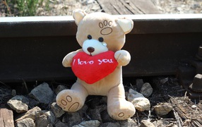 Toy bear with a red heart sitting on the rails